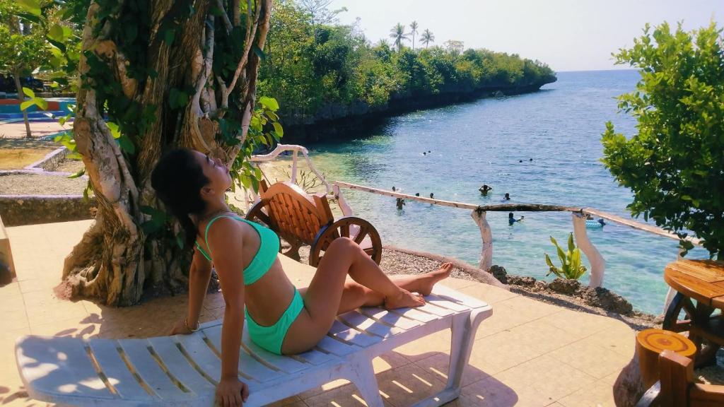 a young girl sitting on a chair next to the water at Poseidon White Sand Resort & Cave in Santa Rosa