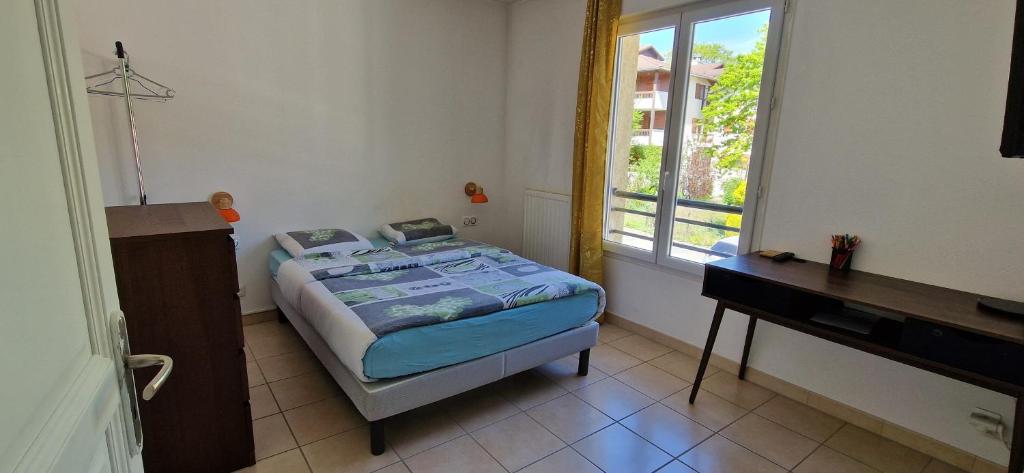 a bedroom with a bed and a desk and a window at Agréable chambre in Prévessin-Moëns