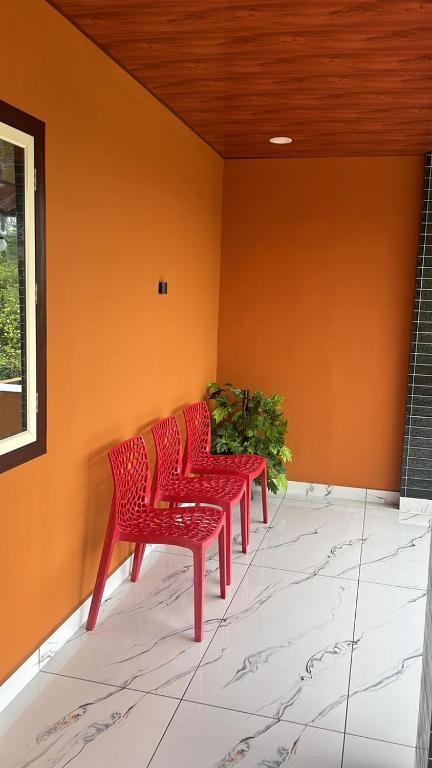 three red chairs in a room with an orange wall at brothers holidayas vagamon in Vagamon