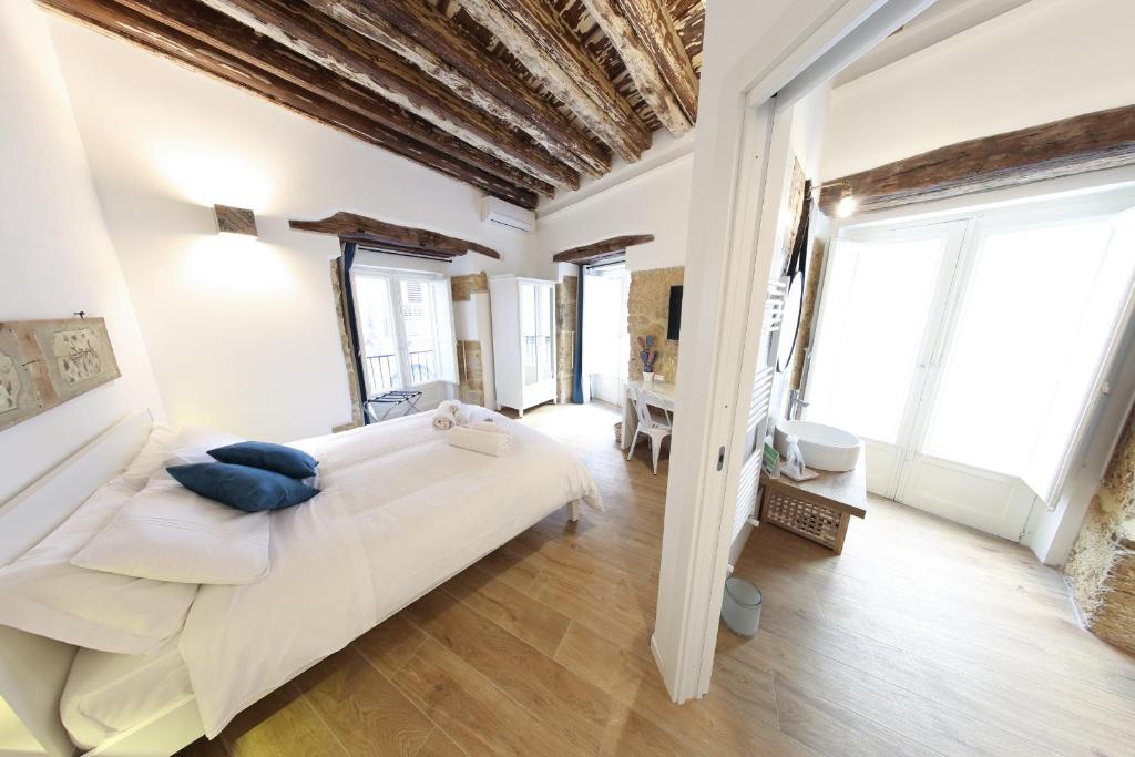 Bedda Mari Rooms & Suite في باليرمو: غرفة نوم بيضاء مع سرير كبير ونوافذ كبيرة