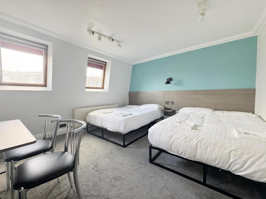 a bedroom with two beds and a desk and a chair at Plaza Hotel in London