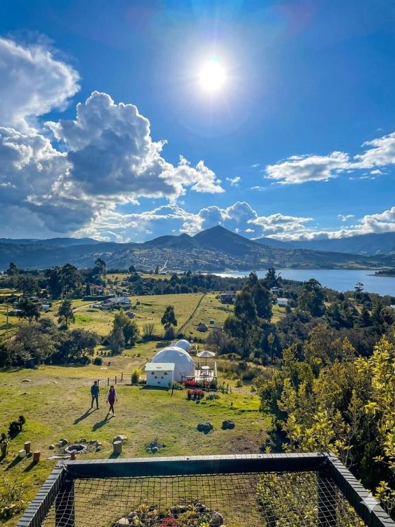 a view of a field with a tent and a lake at Glamping La Villa in Guatavita