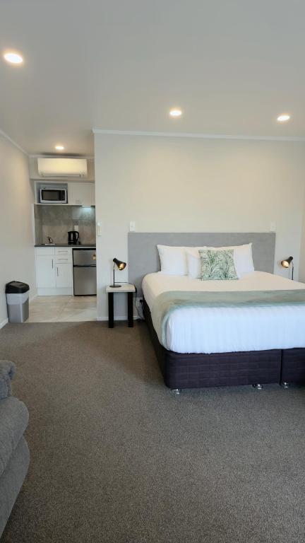 a bedroom with a large bed and a kitchen at BK's Pohutukawa Lodge in Whangarei
