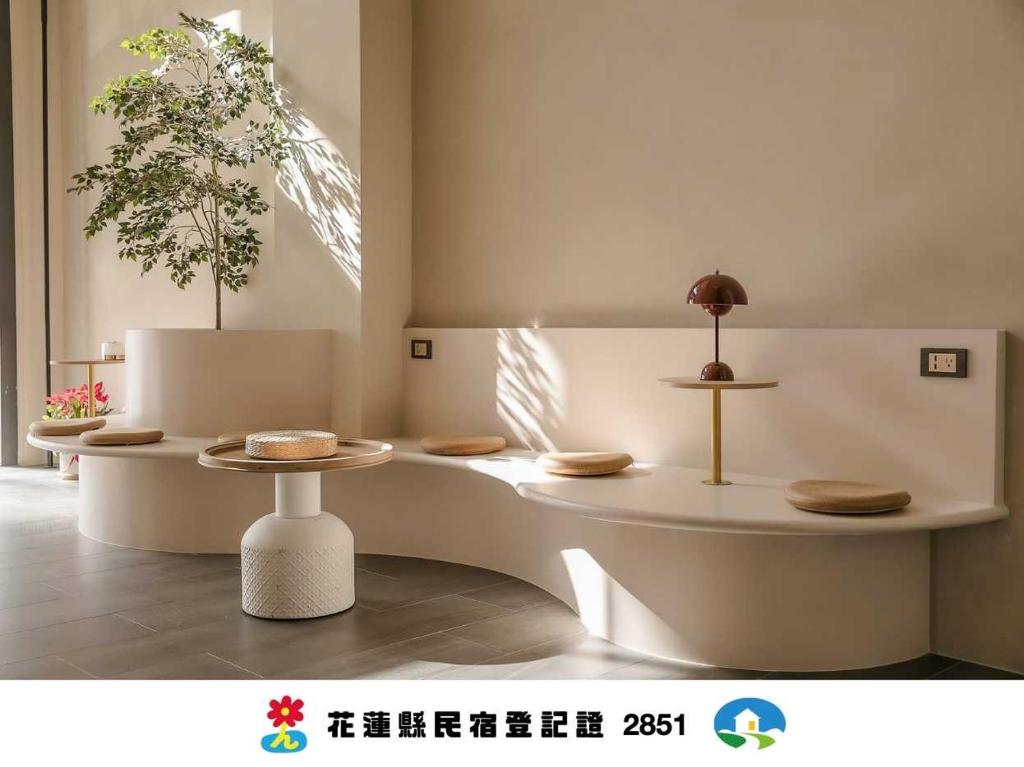 a white room with two tables and a plant at Yuzhi Wenlv B&B in Hualien City