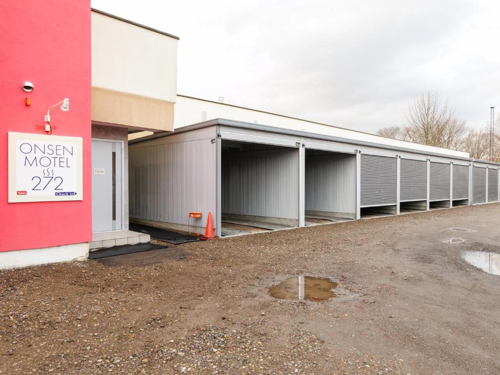 a row of garages in a parking lot next to a building at Tabist ONSEN MOTEL272 in Naka-shibetsu