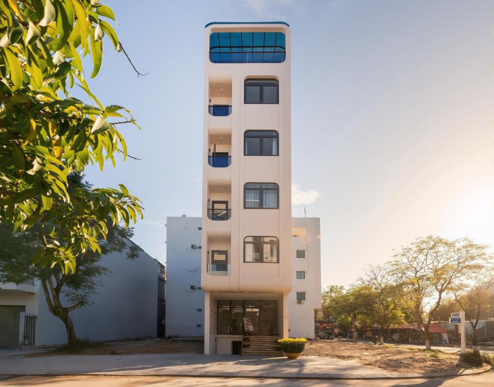 a tall white building with a window at Cossy Home by BRIO in Danang