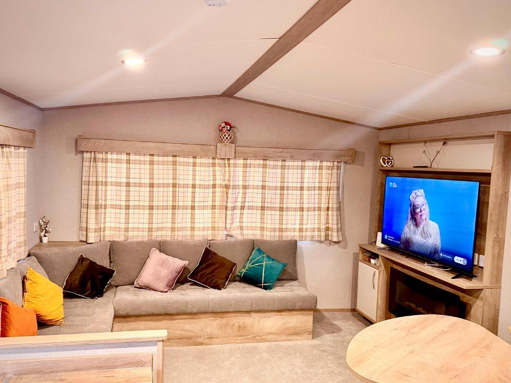 a living room with a couch and a flat screen tv at Diamond Touch Home in Saint Osyth