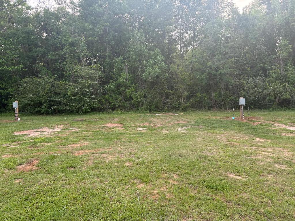 a large grass field with trees in the background at RV Sites at Off the Road Oasis in Lufkin