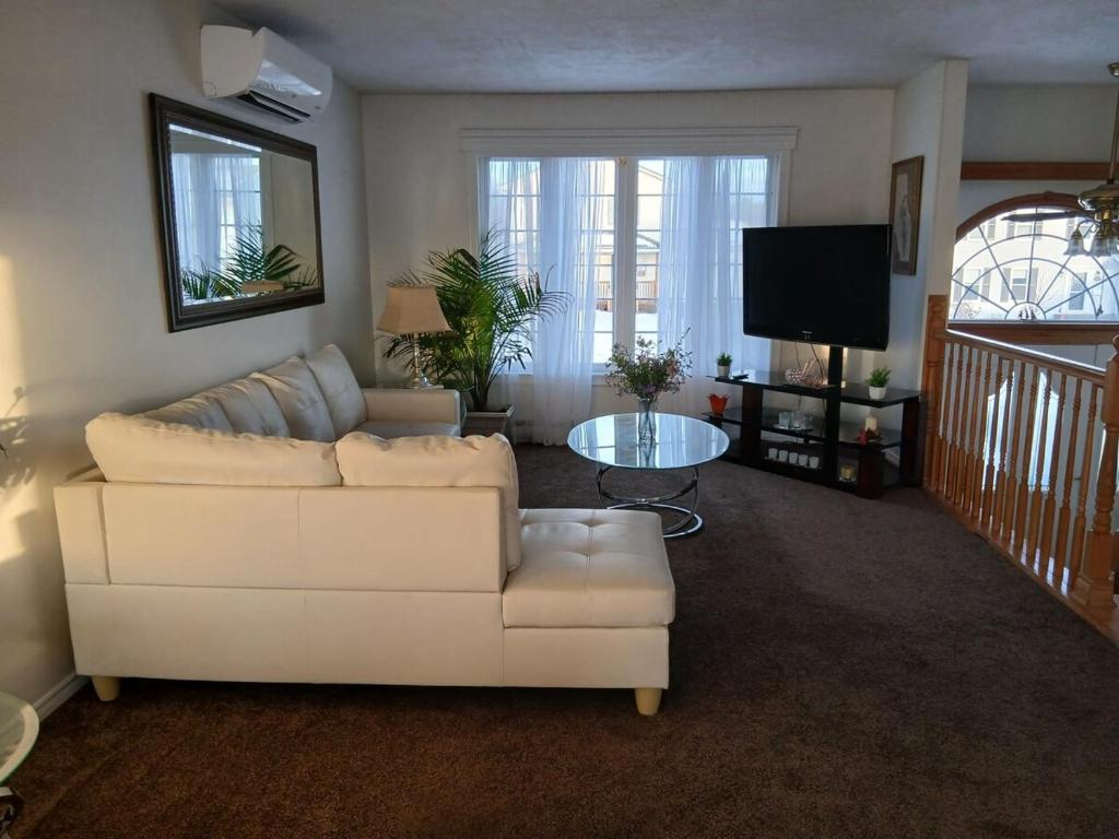 a living room with a white couch and a tv at Home Away From Home in Moncton