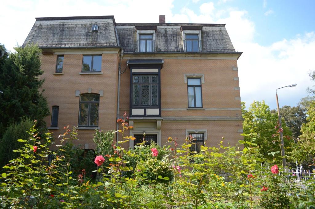 una vieja casa de ladrillo con flores delante en Hummel Hostel - Historische Stadtvilla mit Garten en Weimar