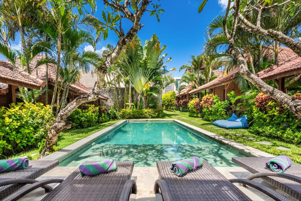 a swimming pool with chaise lounge chairs and a resort at Orora Bungalows Batu Bolong Canggu in Canggu