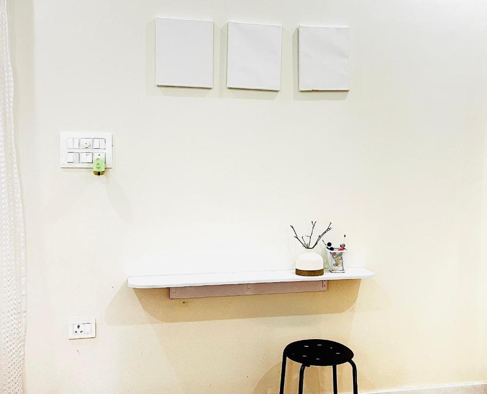 a white wall with a table and a black stool at Satkarma in Rishīkesh
