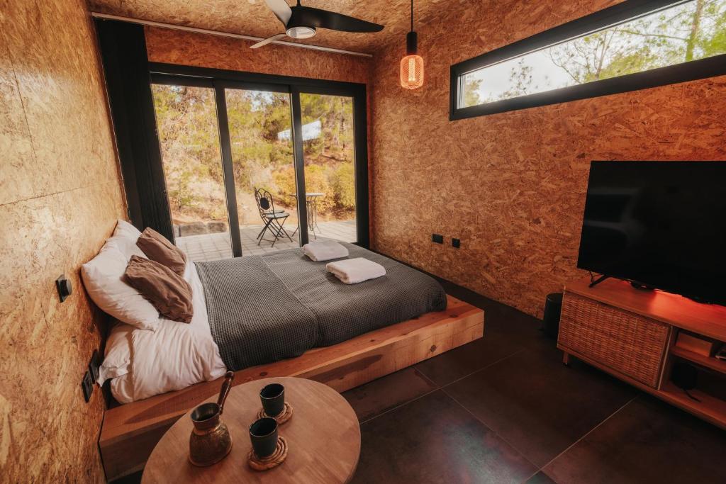 a bedroom with a bed and a tv and a table at Secluded design cabin forest retreat in Cyprus in Kappedhes