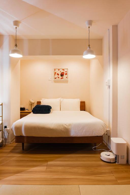 a bedroom with a bed with white sheets and two lights at Shiki Villa Beppu in Beppu