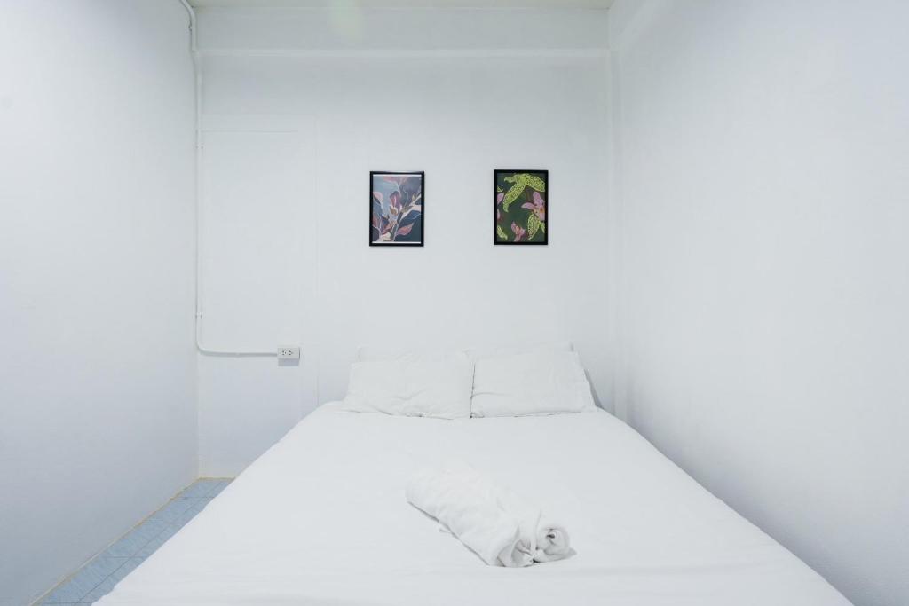 a white bed in a white room with two pictures at zNAP Ekkamai BTS เอกมัย 42 in Bangkok