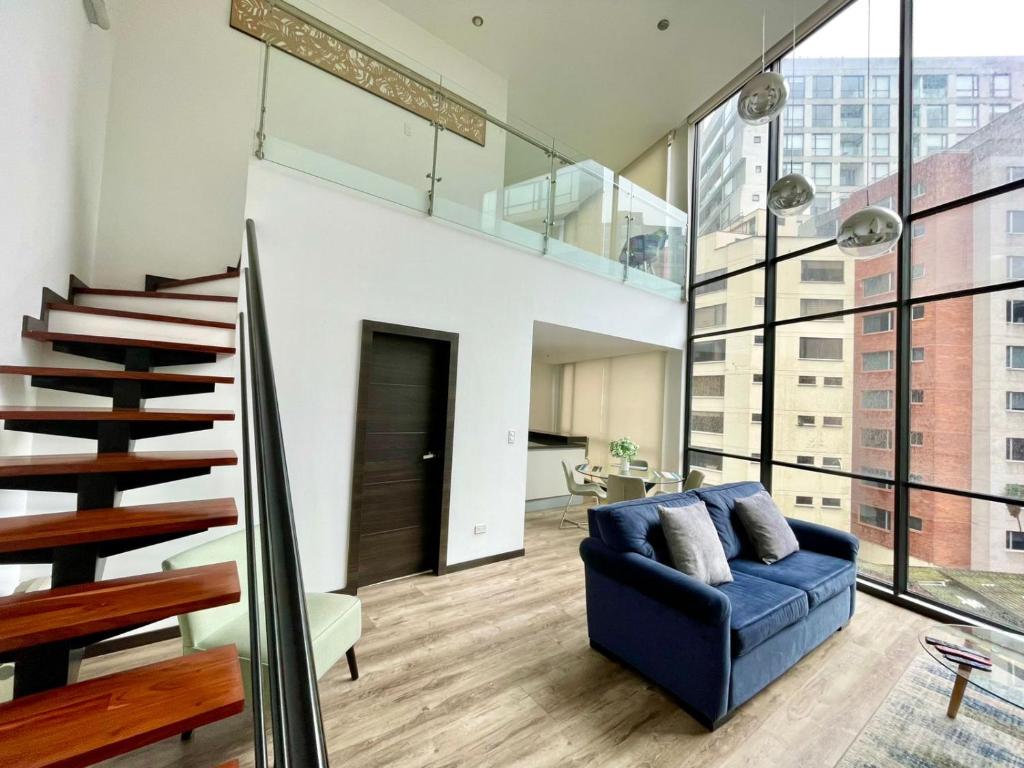 a living room with a blue couch and stairs at ESPECTACULAR LOFT in Quito