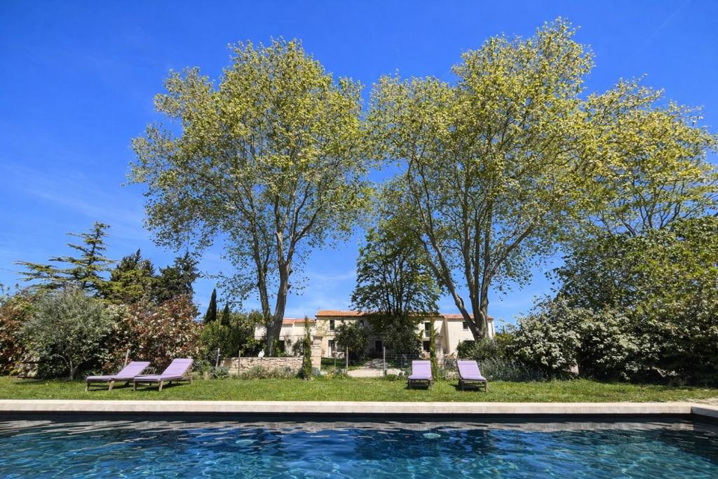 a pool with two lounge chairs and two trees at MAS DES 2 PLATANES in Arles
