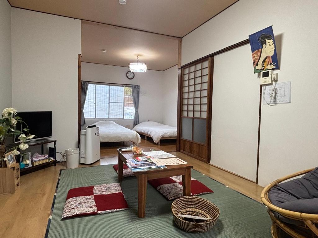 a living room with a table and a bedroom at ゲストハウス樹 in Shingū