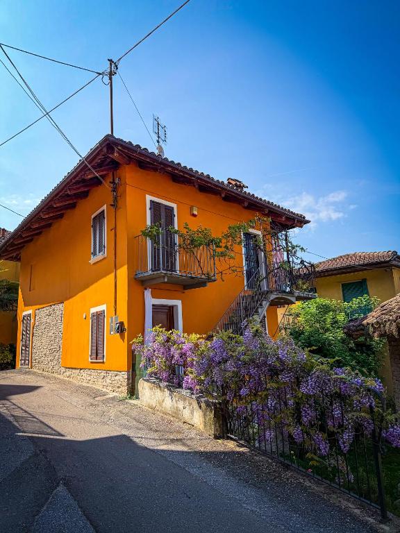 an orange house with purple flowers in front of it at Maison Orange - Dimora nelle Langhe in Neive