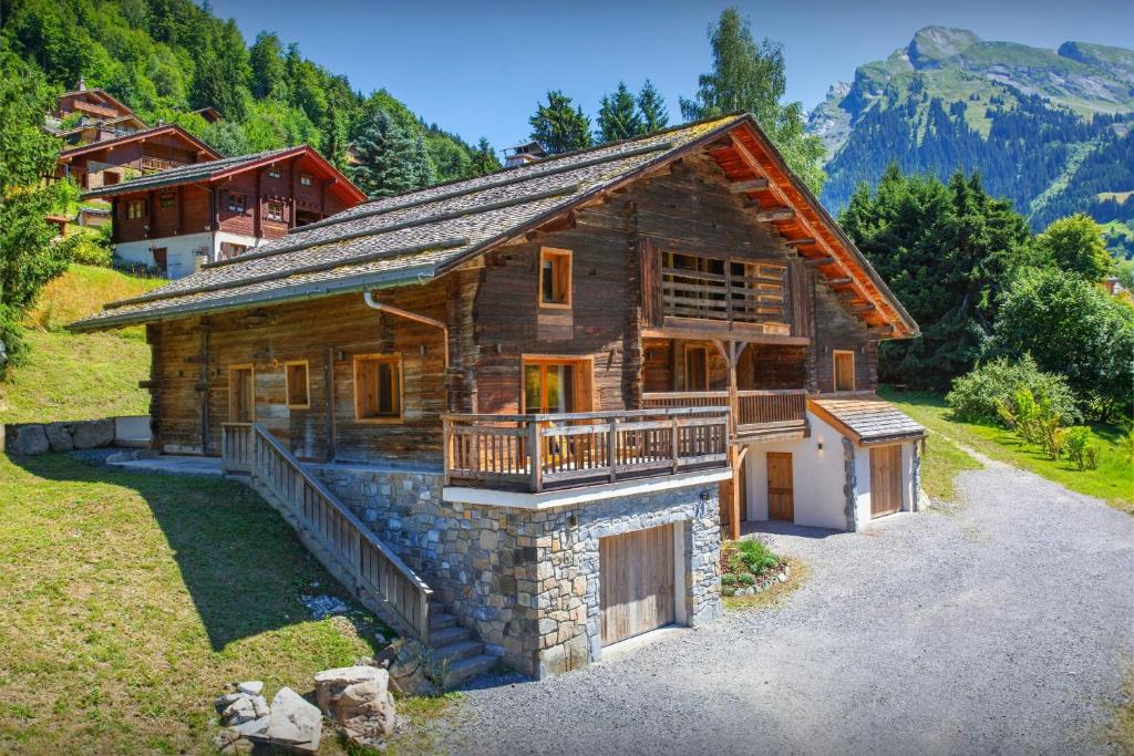 a log cabin with a balcony and a house at Chalet Backflip - OVO Network in La Clusaz