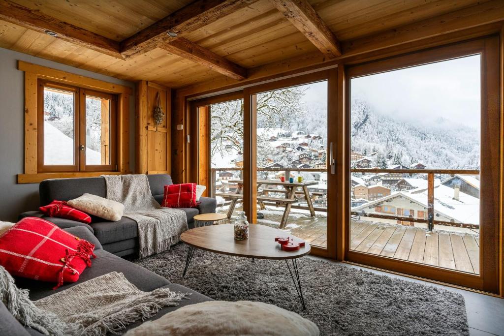 a living room with a couch and a large window at Le Petit Capricia - OVO Network in La Clusaz