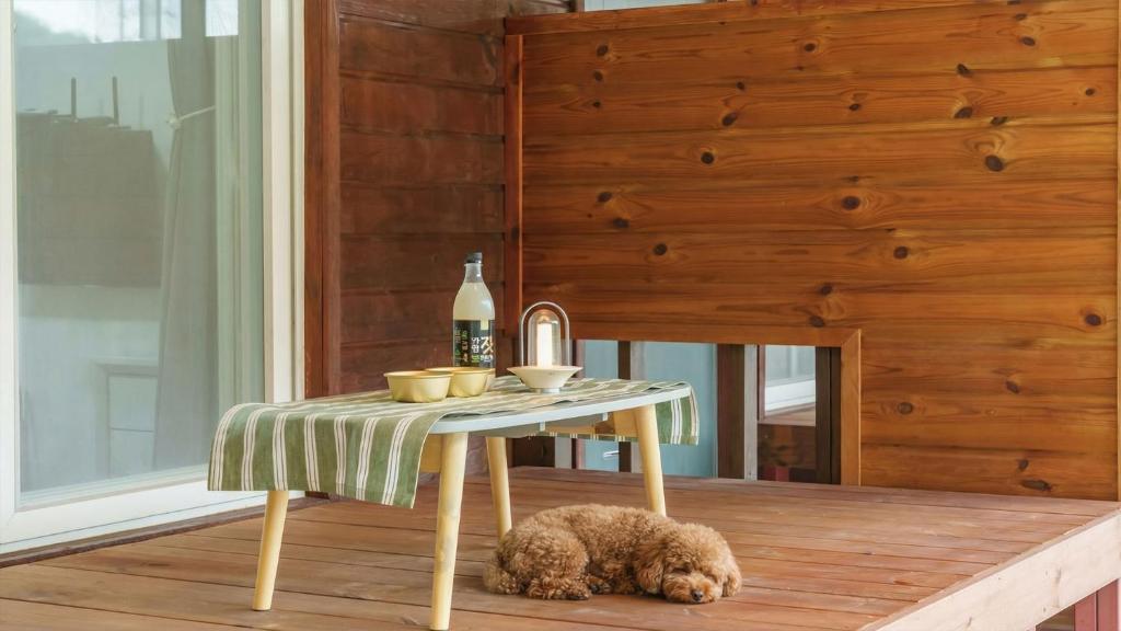a small table with a dog sleeping on a wooden floor at Gapyeong Nature Pension in Gapyeong