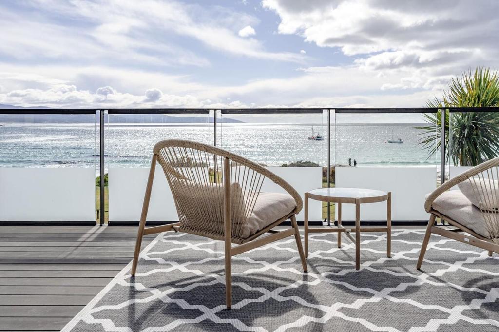 two chairs and a table on a balcony with the ocean at Elevation in Bicheno