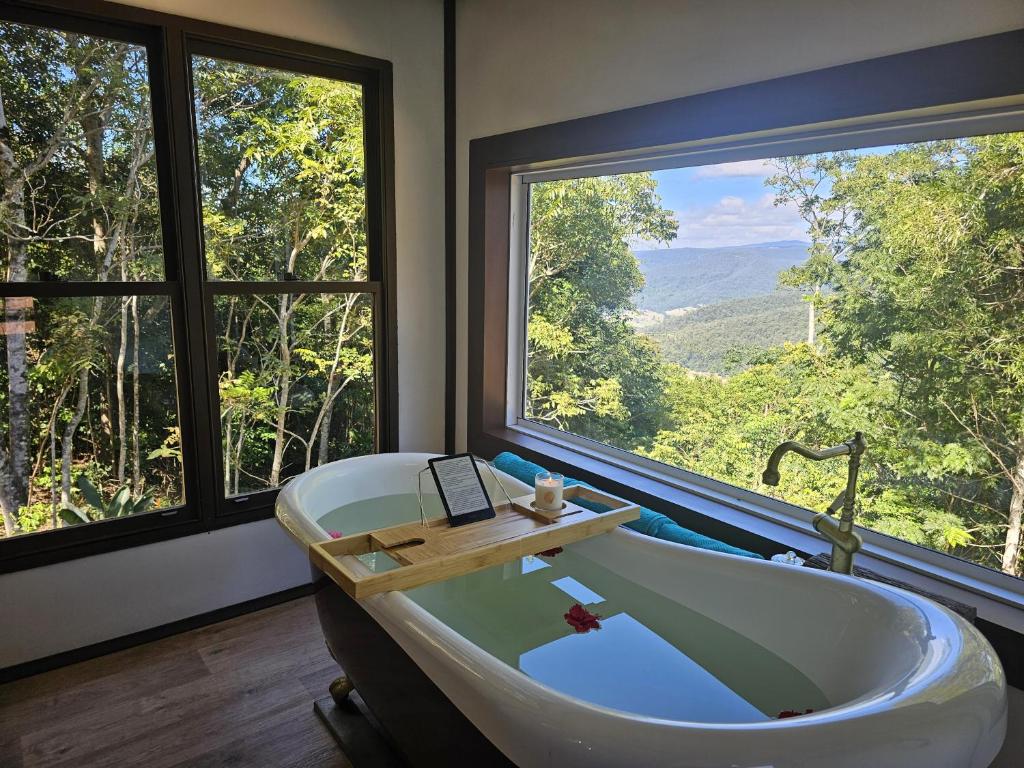a bath tub in a room with a large window at Clouds Serenity in Beechmont