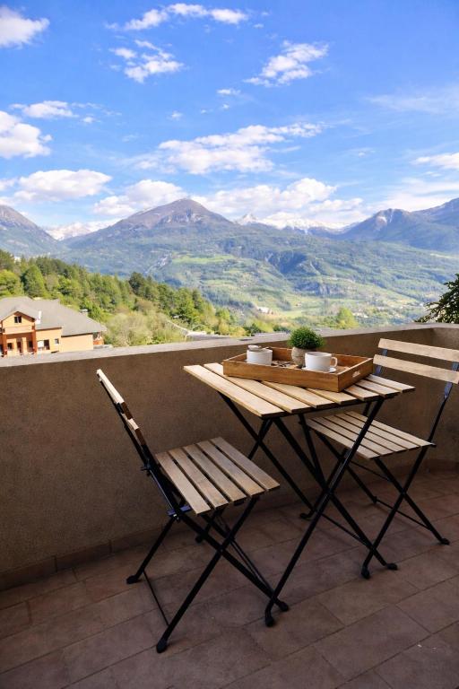 a table and two chairs on a balcony with mountains at Vue montagne exceptionnelle T2 Cosy avec Balcon proche du lac in Embrun