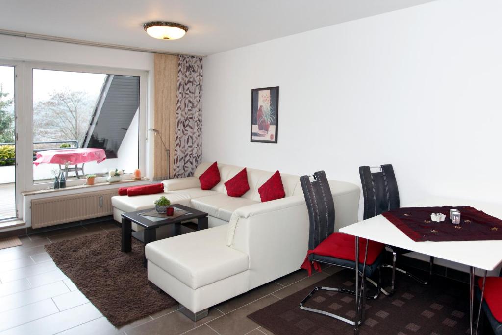 sala de estar con sofá blanco y almohadas rojas en Ferienwohnung Inge Steinrücken, en Winterberg