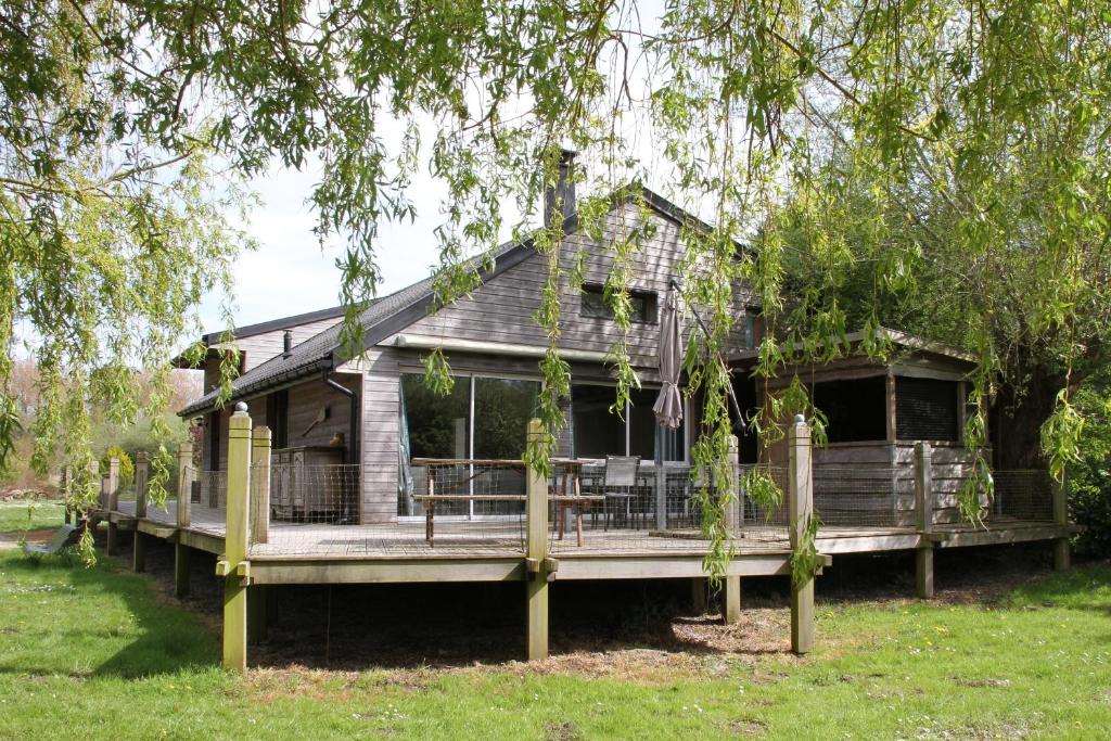 a house with a large deck in the grass at Le Chalet de Merlimont in Merlimont