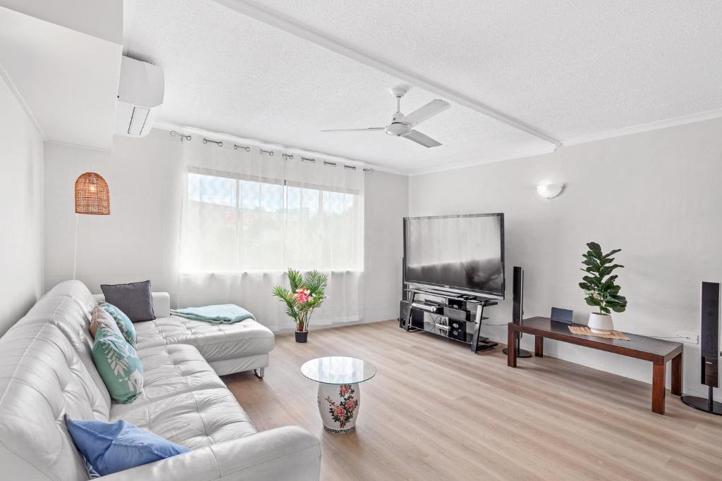 a living room with a white couch and a flat screen tv at Capricorn Whitsunday in Cannonvale