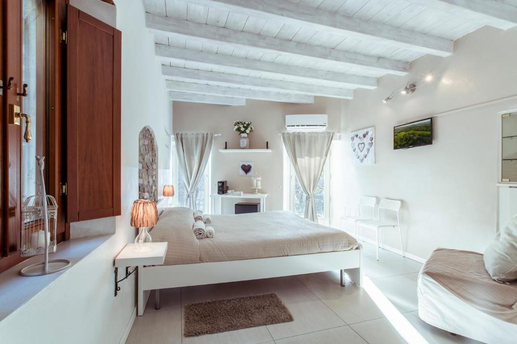 a white bedroom with a bed and a table and chairs at La Piccola Matilde in Desenzano del Garda
