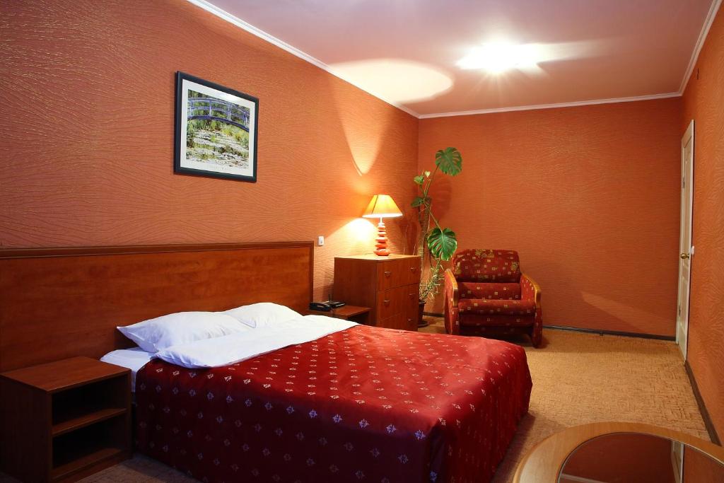 
a bedroom with a bed, chair, desk and a lamp at Ukrainian Hotel Service Apartments in Kyiv
