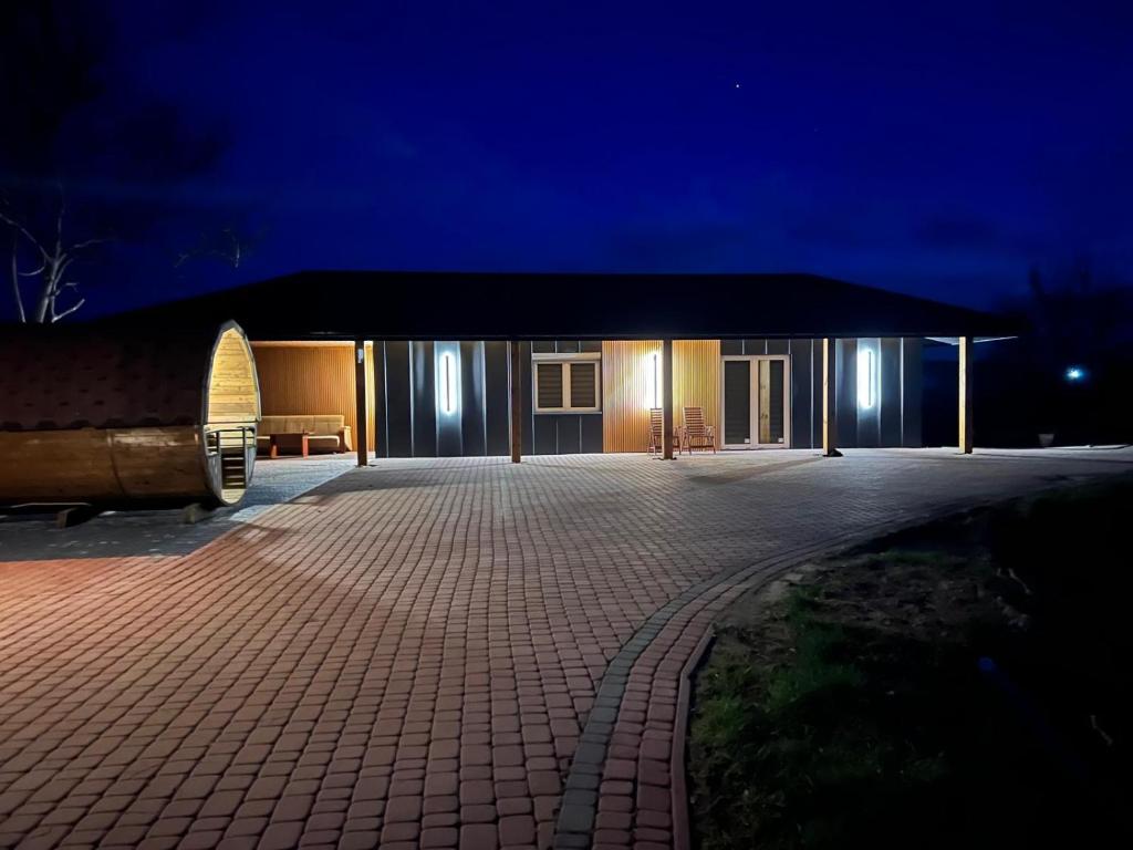 a building with a brick driveway in front of it at night at Domek na łowisku in Adamówka
