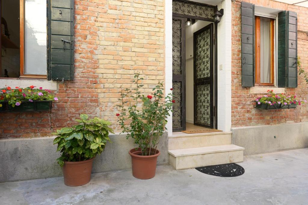 Un edificio con dos plantas en macetas delante de una puerta. en Secret Garden Venice, en Venecia