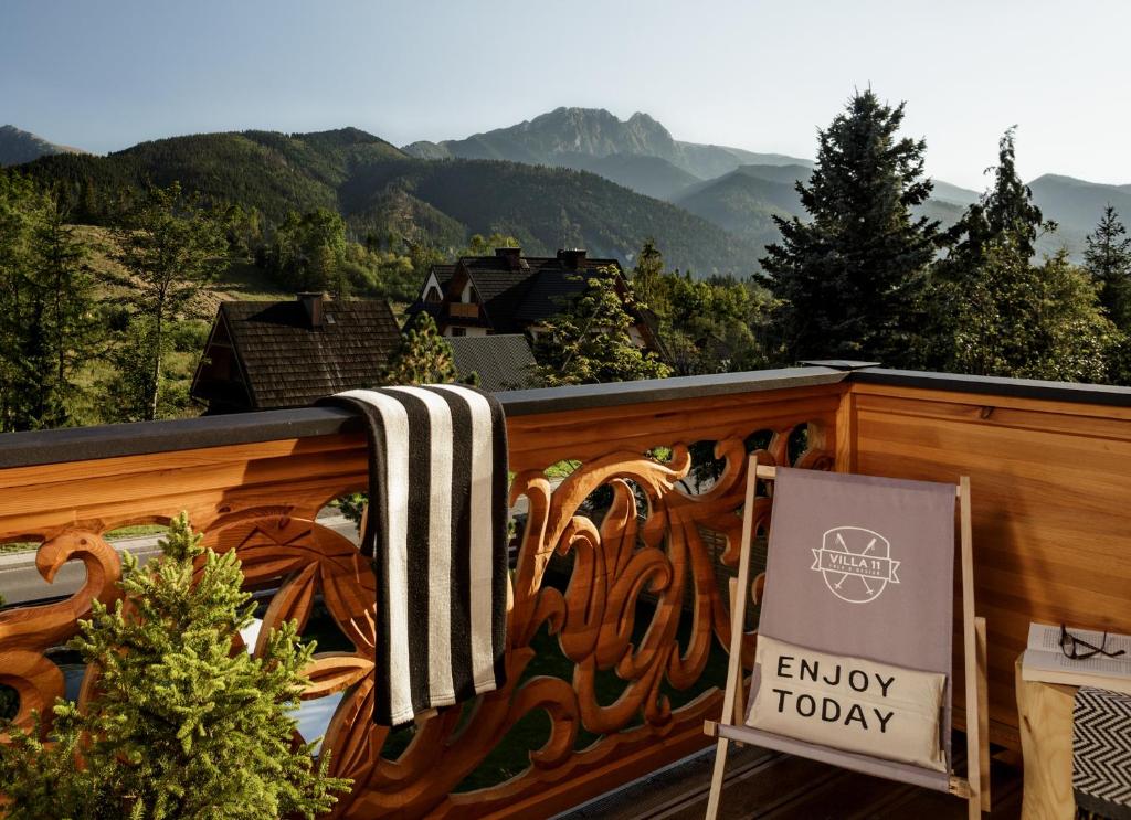 a sign on a balcony with mountains in the background at Villa 11 Folk & Design in Zakopane