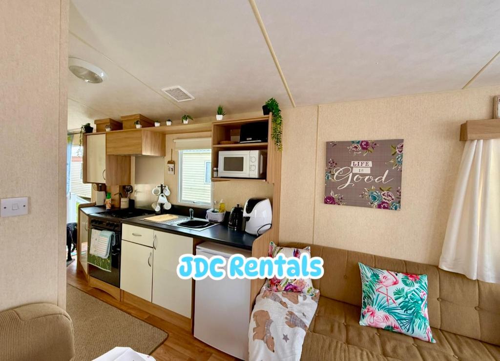 a small kitchen with a stove and a microwave at Palins - KC19 in Kinmel Bay