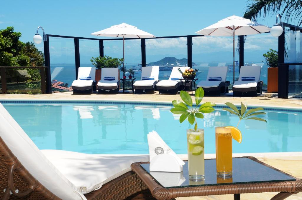 a table with drinks on it next to a swimming pool at Costa do Sol Boutique Hotel in Búzios