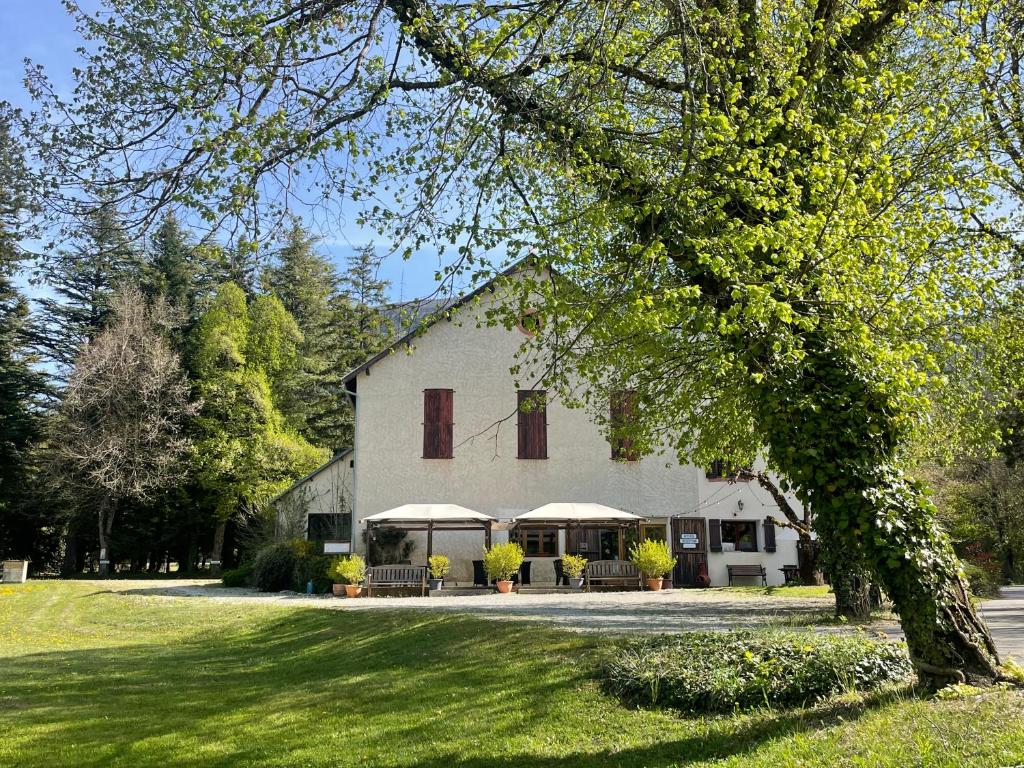a large white house with tables and chairs in a yard at La Source in Saint-Pierre-dʼArgençon