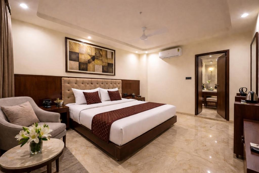 a hotel room with a bed and a chair at Hotel Liora in Rajkot