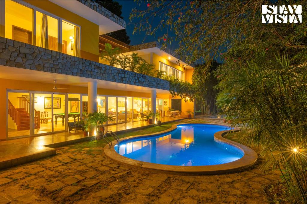 a swimming pool in front of a house at night at StayVista at The Hideout Farms with Lawn and private Pool in Kurukshetra