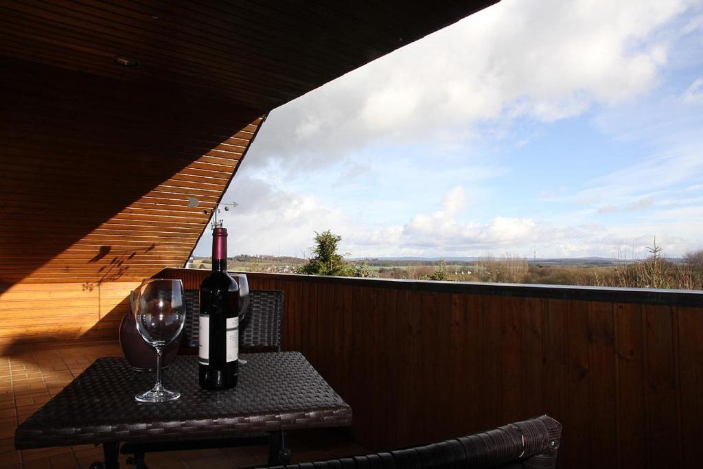 una mesa con una botella de vino y una copa en Ferienwohnung Panoramaweg, en Sohren