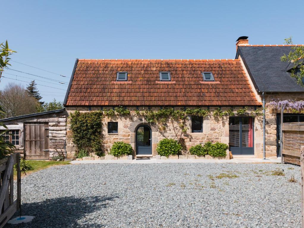 a stone house with a red roof on a gravel driveway at Maison Vintage de Kerlipot in Ploubezre