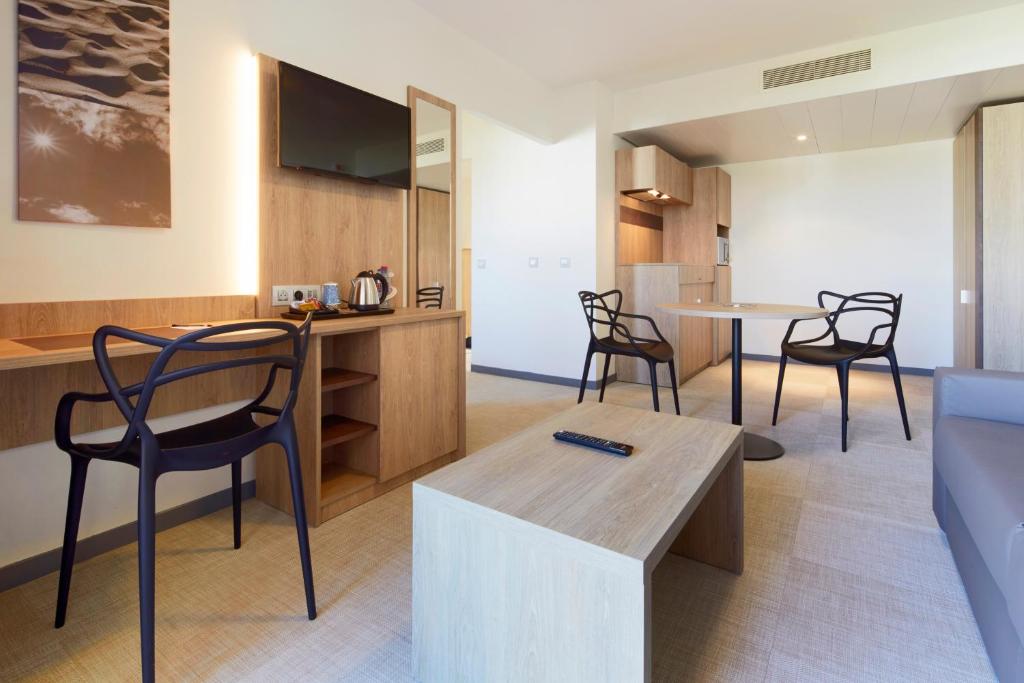 a kitchen and dining room with chairs and a table at Kyriad Prestige Residence & Spa Cabourg-Dives-sur-Mer in Dives-sur-Mer