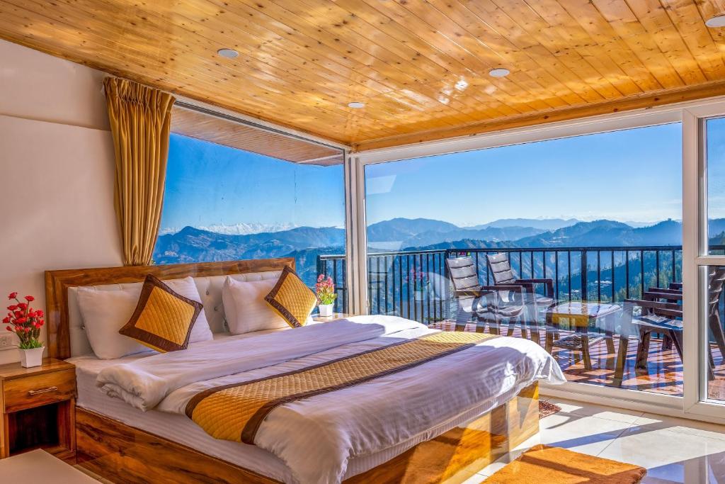 a bedroom with a bed and a balcony with a view at Vamitag Inn in Shimla