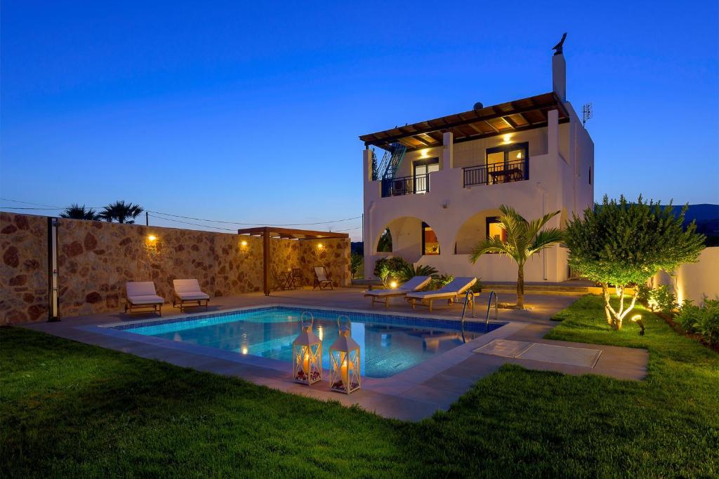 a villa with a swimming pool at night at Deep Blue Villa in Lachania
