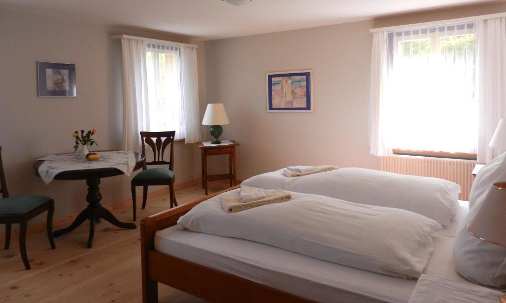 a bedroom with two beds and a table and a chair at Hotel Rigi Klösterli in Rigi Klösterli