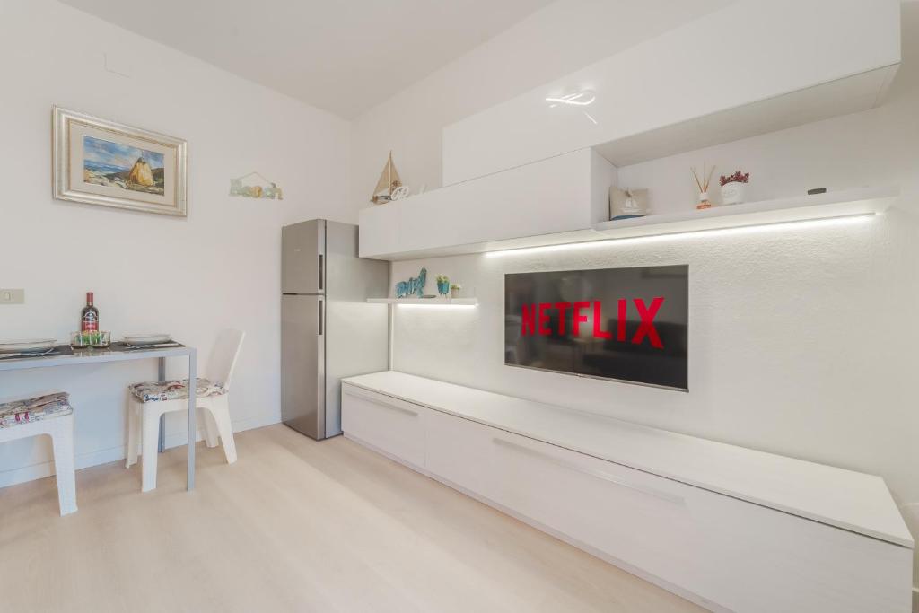 a white living room with a tv on a wall at Marina Vip Anna in Procchio