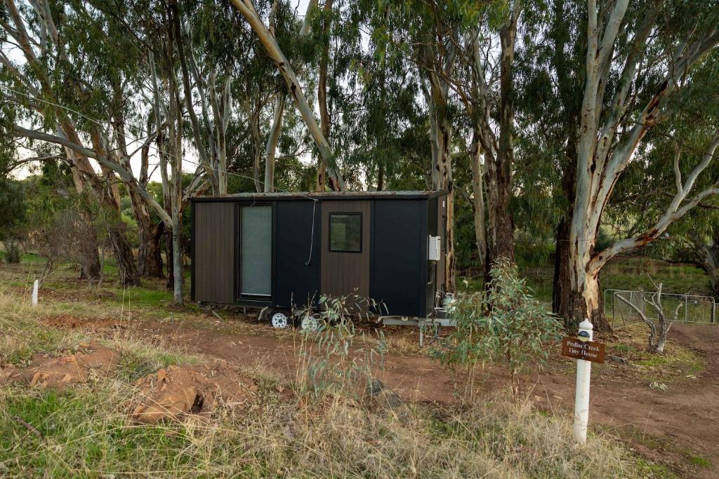 a black tiny house sitting in the woods at Pedlar Creek Tiny House by Tiny Away in McLaren Vale